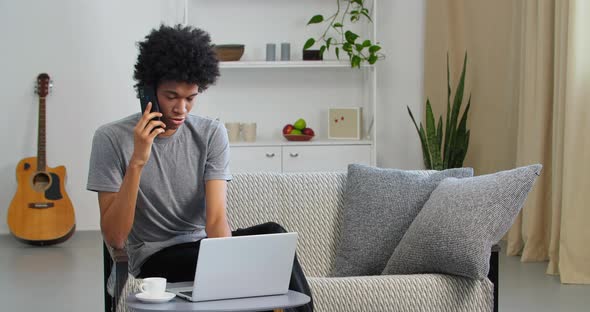 Serious Afro American Business Man Student Guy Talking on Mobile Phone Use Laptop for Remote Work