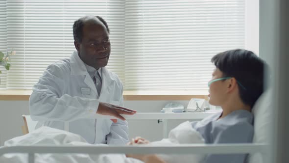 Multiethnic Doctor and Patient Talking in Hospital Ward