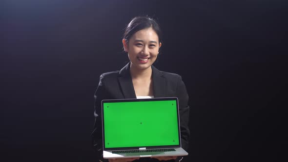 Asian Woman In Business Suit Holding Laptop Computer With Green Screen In The Black Screen Studio