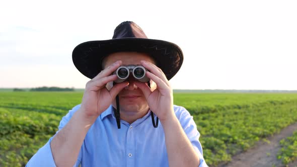 Surprised Look of a Young Man in Binoculars on the Field at Sunset