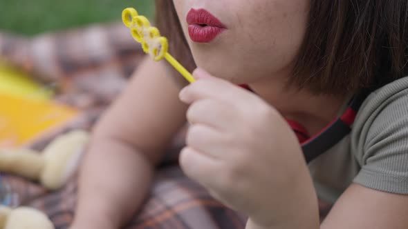 Lips of Unrecognizable Caucasian Little Woman Blowing Soap Bubbles Outdoors