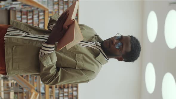 African American Man Reading Book in Library