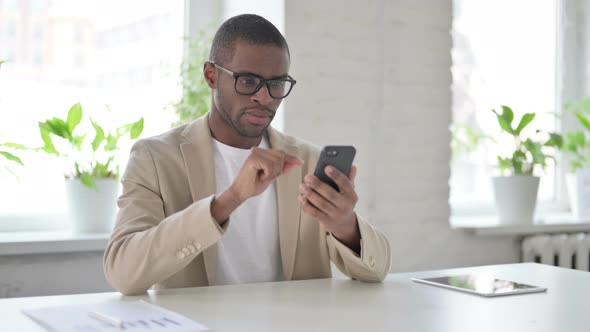 Attractive African Man Using Smartphone in Office