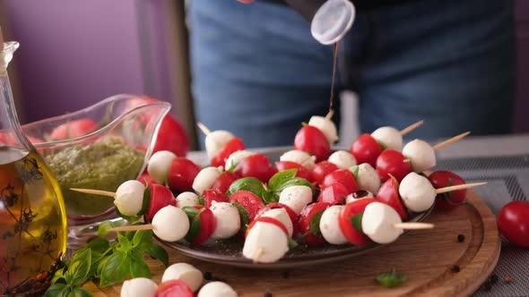 Pouring Balsamic Sauce on Caprese Canapes with Cherry Tomatoes and Mozzarella Cheese Balls