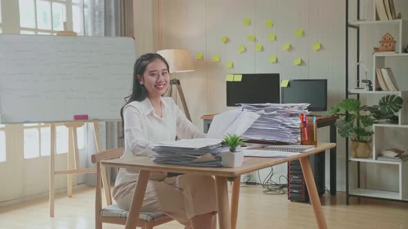 Asian Woman Smiling To Camera While Working With Documents At The Office