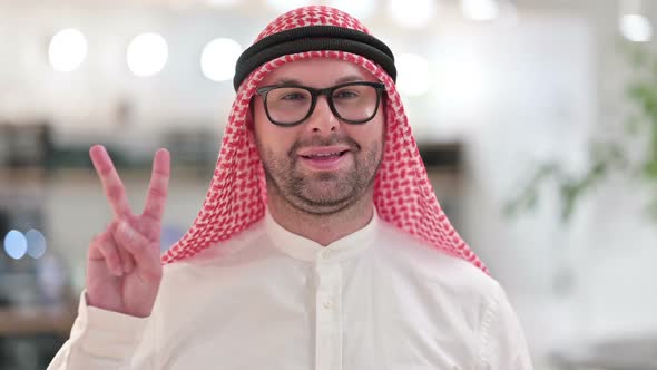Successful Young Arab Businessman Showing Victory Sign with Hand