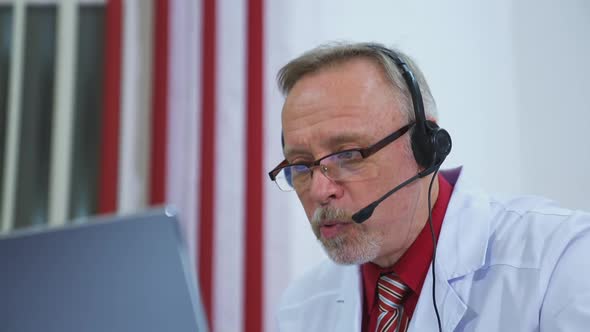 Senior physician talks to camera consulting patient online in web chat.