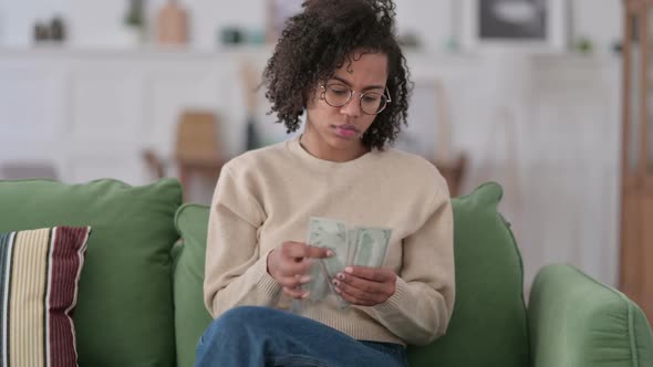 Successful African Woman Counting Dollar on Sofa