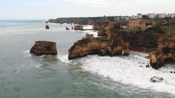 Algarve rocky eroded cliffs in the Atlantic coast in Student Beach In Lagos, Portugal - Aerial Orbit