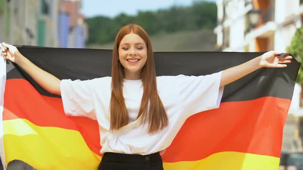 Joyful Red-Haired Teen Waving German Flag and Smiling on Camera, Patriotism