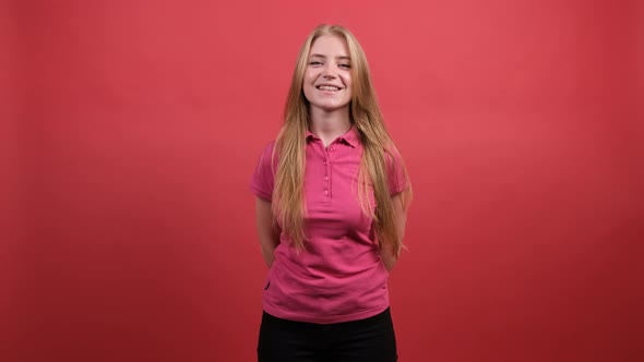 Pretty Girl Looking at Camera with a Smile, Isolated Over Red Background.