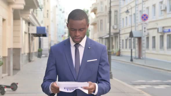 African Businessman Reading Document While Going to Office