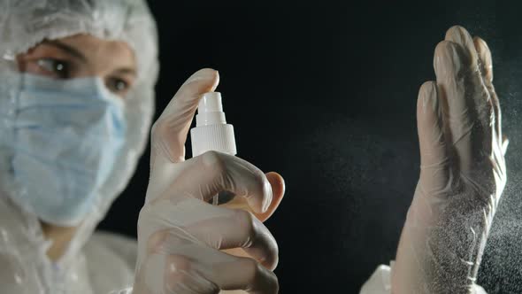Male Medic in a Medical Mask and Protective Suit Treats His Hands with an Antiseptic. Coronavirus