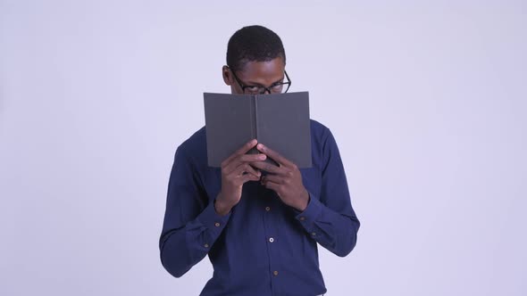 Young African Nerd Businessman with Eyeglasses Covering Face with Book