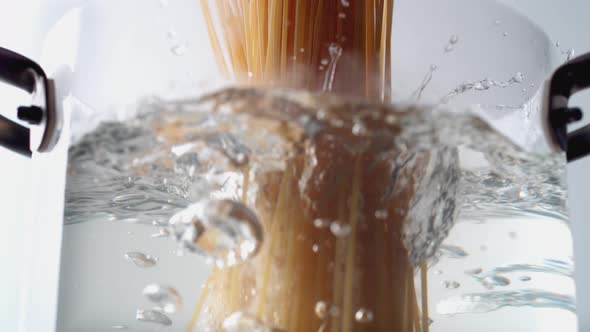 Camera follows cooking spaghetti noodles in boiling water. Slow Motion.