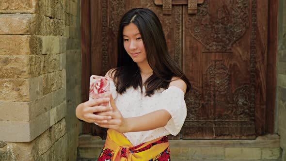 Teenage Chinese tourist explores a temple in Bali.