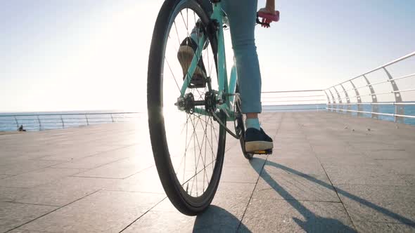 Young Stylish Woman Cyclist Enjoying Fixed Gear Bike Riding Outdoors at Sunrise Near the Sea Close