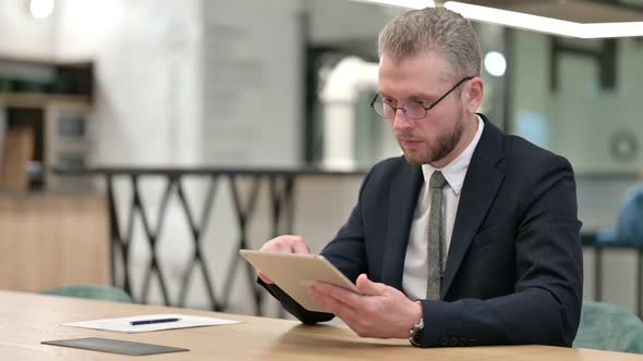 Serious Professional Young Businessman Using Tablet in Office