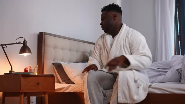 Confident Handsome African American Man Sitting on Bed Checking Time on Smartphone Walking Away