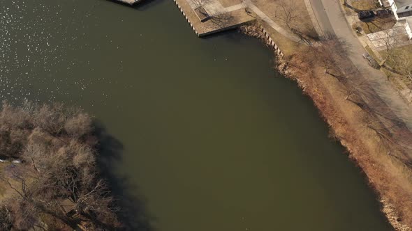 An aerial shot of a pond in a suburban neighborhood on Long Island, NY.  The camera tilted down, pan