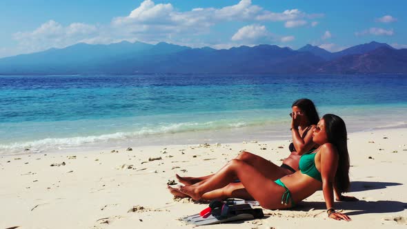 Modern happy ladies on vacation by the sea at the beach on summer white sandy and blue background 4K