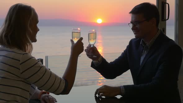 Couple toasting with wine and enjoying sunset over sea