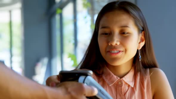 Teenage girl making payment through NFC