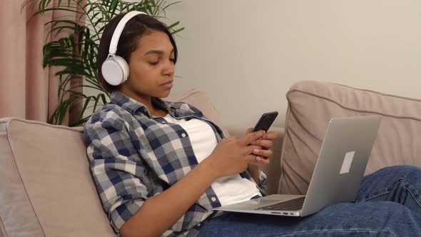 Woman Lying Down Listening to Music in Headphones with a Phone in Her Hands