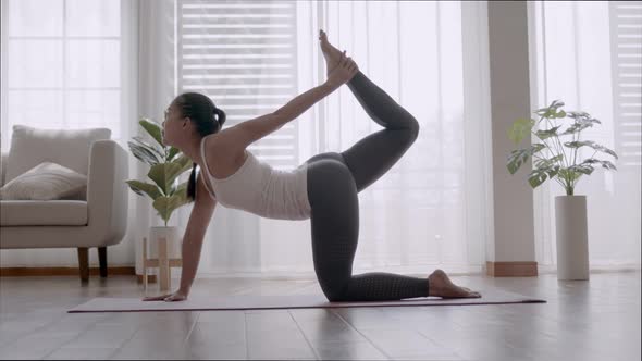 Asian woman practicing yoga pose Bow at home.