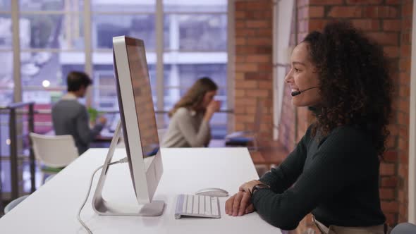 Creative businesswoman wearing headset talking in modern office