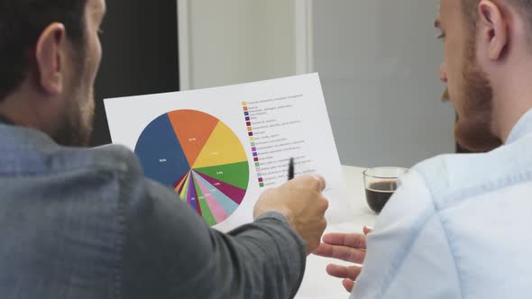 Close Up of Male Business Partners Examining Printed Diagram