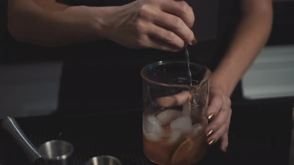 close up of bartender mixing craft cocktail in ice with tall bar spoon