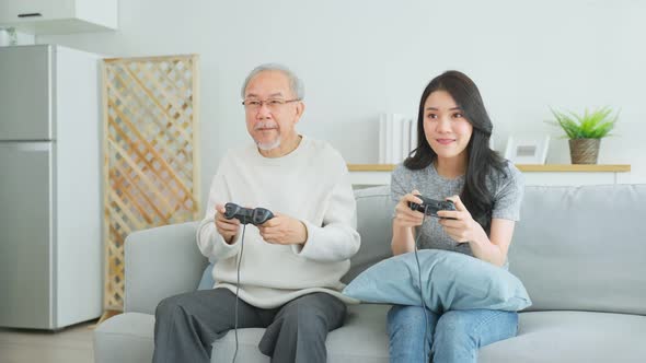 Asian senior father and daughter enjoy playing game together in house.