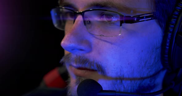 Portrait of a Gamer with Glasses Playing an Online Video Game and Commenting Into a Microphone