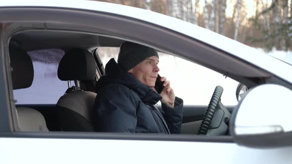 Young Man Talking on Phone Inside Car in Winter