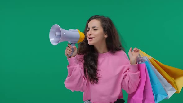 Young Beautiful Woman Speaks in Loudspeaker To Announce and Advertise with Shopping Bag on Green