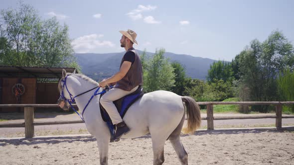 Horse rider riding his white horse on the farm.