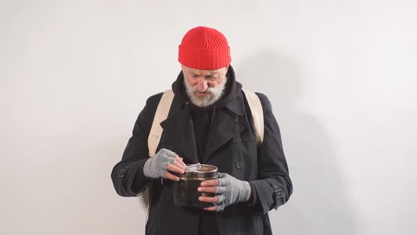 Portrait of Homeless Beggar with Cup for Money Finds Paper Money in His Cup
