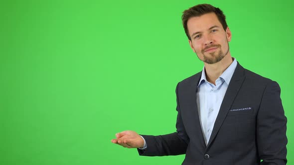 A Businessman Puts Out a Hand with a Product, Occasionally Moving It To the Side While He Smiles