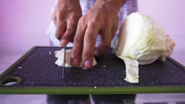 Young man cutting cabbage for salad