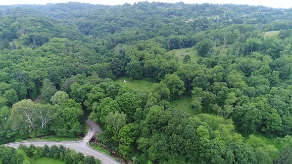 A slow rising aerial establishing shot of the Allegheny Mountains and valley. A small country road a