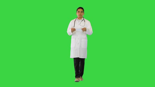 Hispanic Male Doctor Putting on Medical Mask While Walking on a Green Screen Chroma Key