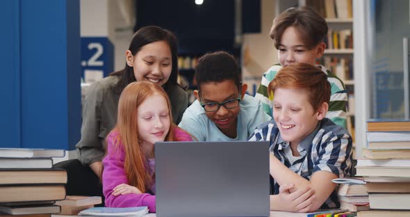 Happy Multiethnic Classmates Using Computer Together in School Library