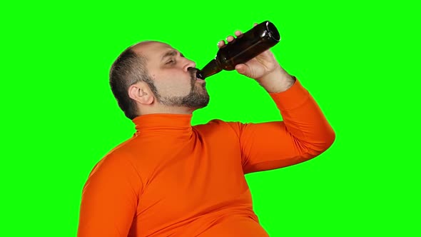 Caucasian Man Holds a Bottle of Beer in His Hands and Drinks with Pleasure, Green Screen. Slow