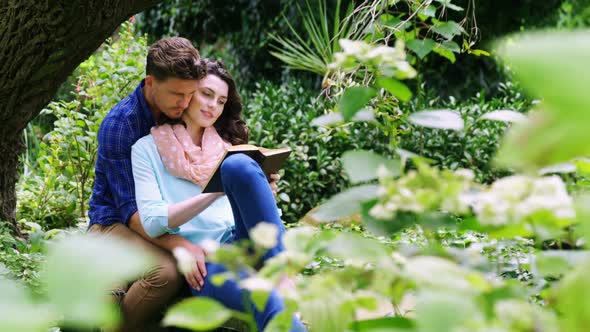 Romantic couple reading novel in park