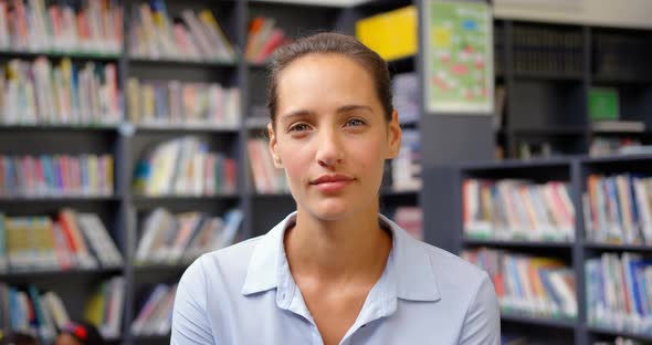 Front view of Caucasian female teacher standing in the school library 4k