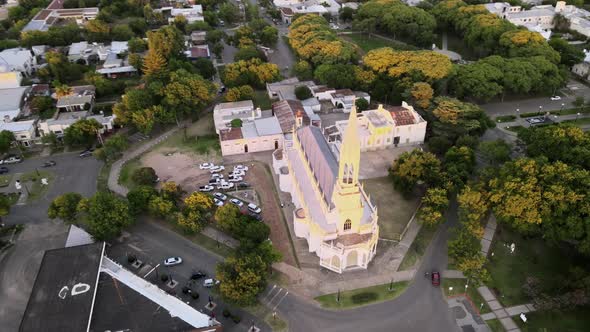 Aerial lowering beautiful neo gothic church surrounded by trees in the middle of Santa Elisa country