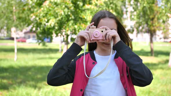 Girl 11 Years Old Takes Pictures with a Toy Wooden Pink Camera