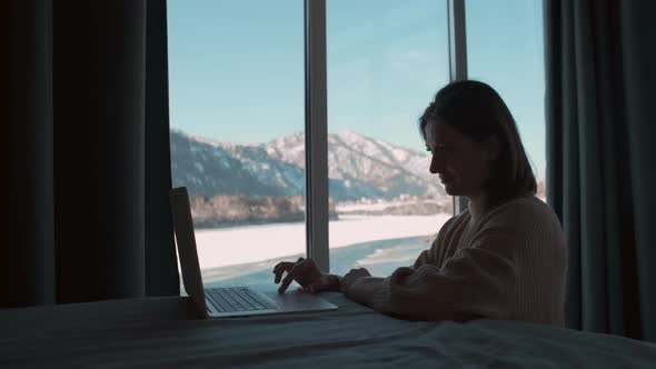 A Woman Works From Home Sitting in the Bedroom By the Window