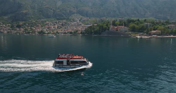 speeding ship with tourists in kotor bay with mountains on background